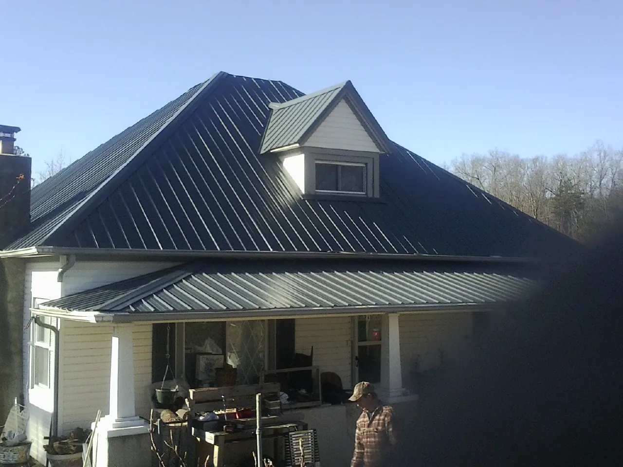 Dark blue standing seam metal roof with a dormer above a front porch in Seaside