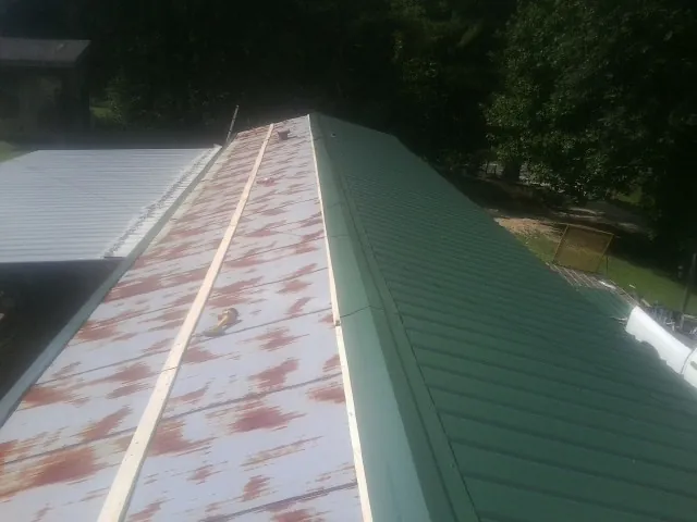 Old rusted panels beside newly installed green metal roofing — Wind Damage Roof Repair by Roofing Brothers in Seaside