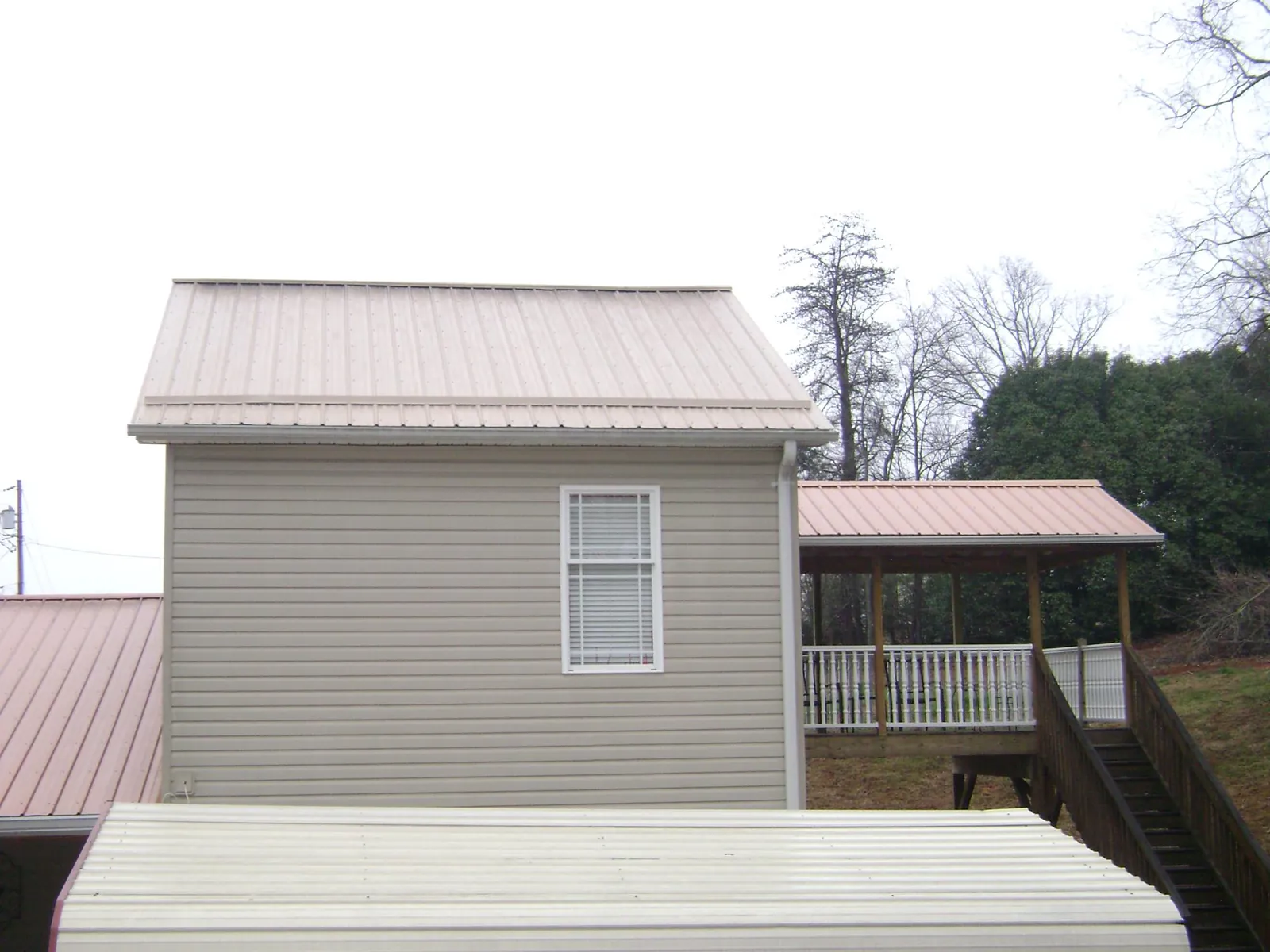 Tan metal roofs on a two story addition and attached porch, from a Roof Replacement job in Seaside