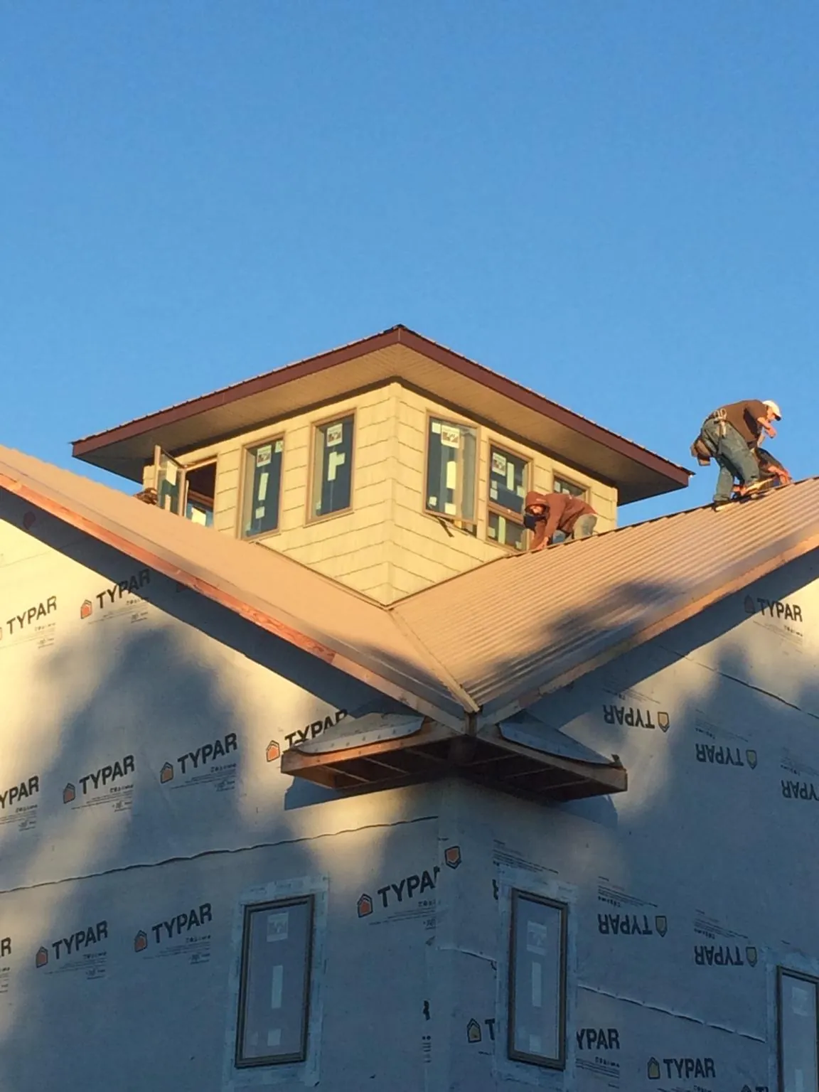 Roofers working around a rooftop cupola on a new metal roof at sunset — Roof Waterproofing in Seaside by Roofing Brothers